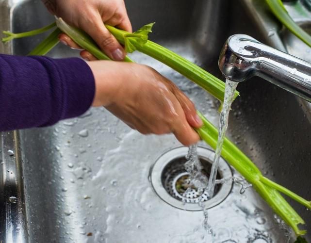 Woman Washing Vegetables In The Sink