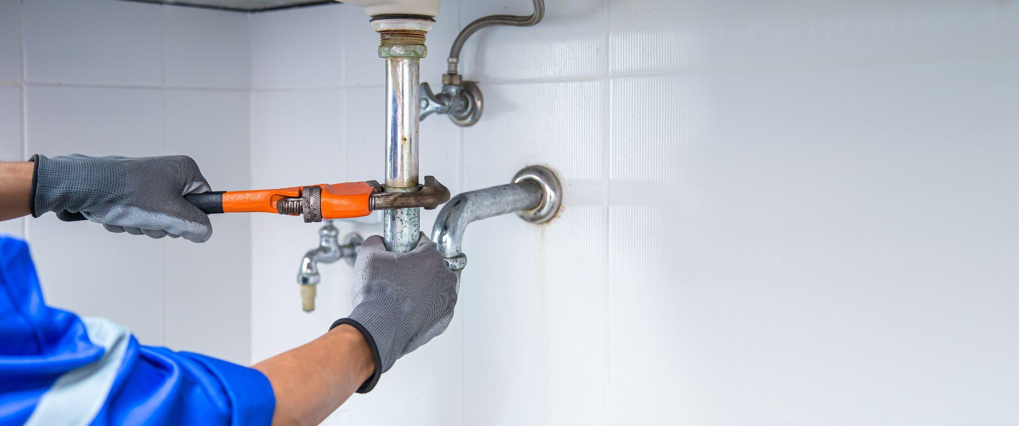 Technician Plumber Using A Wrench To Repair A Water Pipe Under The Sink