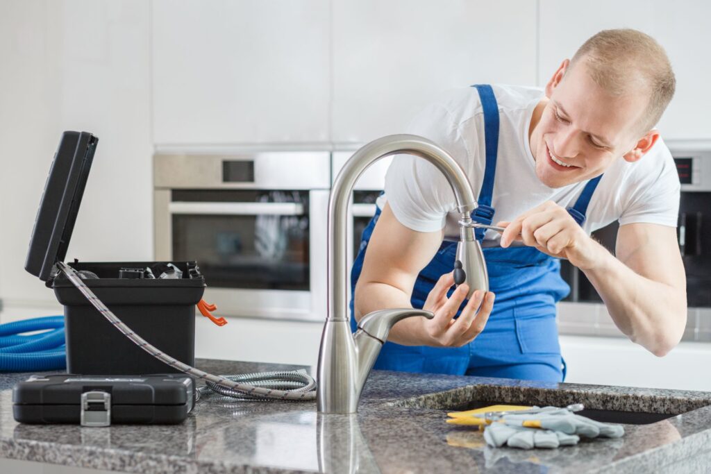 Happy plumber repairing kitchen's faucet