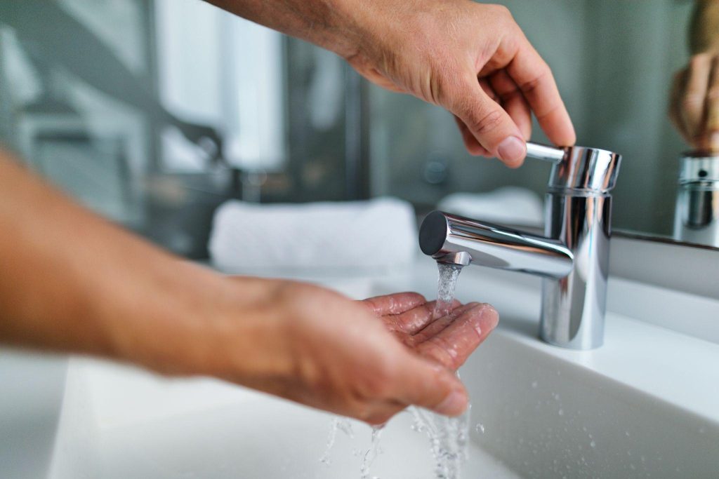 Man washing hands in bathroom sink at home