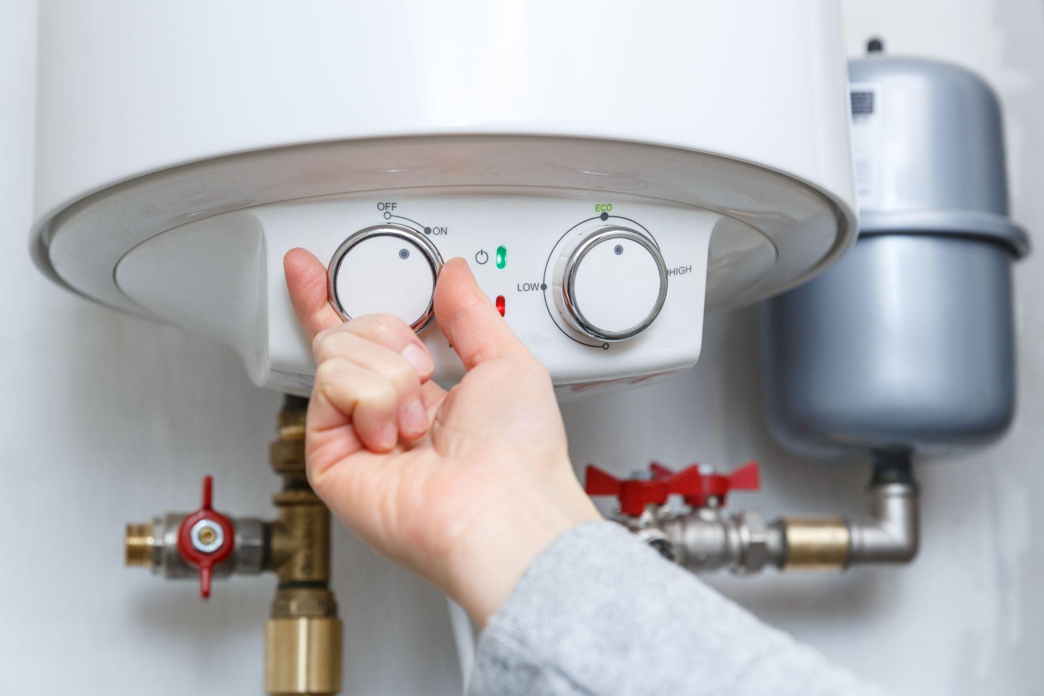 Female hand turning on electric water heater