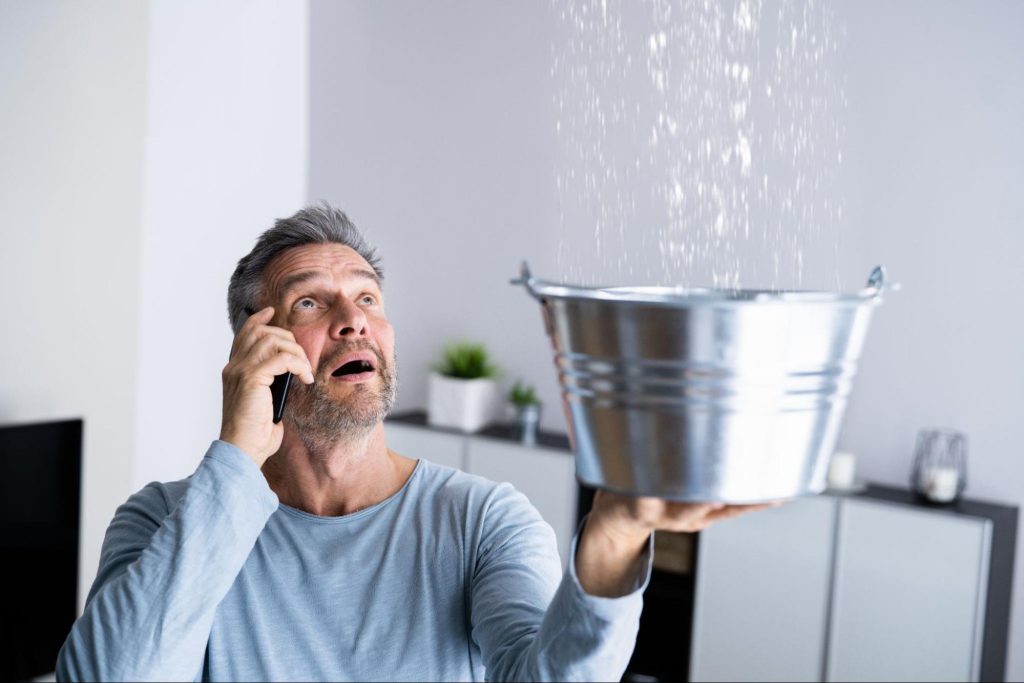 A man holding up a bucket as water comes from the ceiling