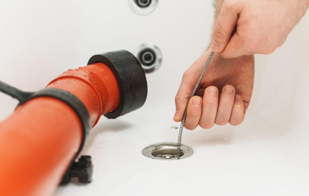 A closeup of a plumber performing a drain cleaning service